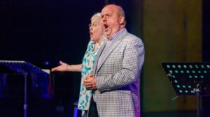 Opera singers Graeme Danby and Valerie Reid perform on stage.