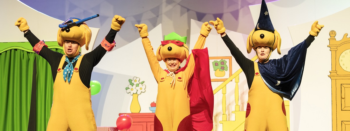 Three actors dressed as dogs hold their hands in the air in a production shot for Spot's Birthday Party (Credit: Tim Dickeson)