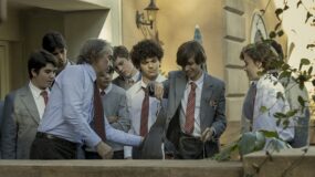 A group of people stand around a penguin in a still from The Penguin Lessons.